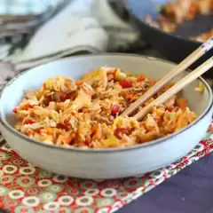 Miseczka pełna aromatycznego nasi goreng z warzywami i kawałkami kurczaka, gotowa do jedzenia pałeczkami.