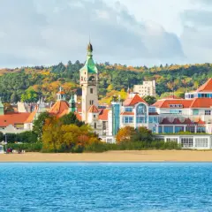 Malownicze widoki na plażę i zabytkowe budynki w Sopocie. Zobacz słynną latarnię morską i kościół na tle jesiennych drzew.