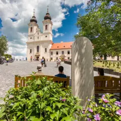 Tihany Balaton: malowniczy plac przed opactwem benedyktynów, z turystami odpoczywającymi na ławkach i podziwiającymi architekturę.