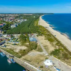 Widok na port i plażę w Władysławowie, z widoczną linią brzegową Jastrzębiej Góry w oddali.