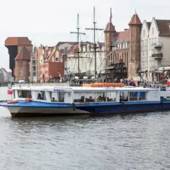 Pasażerski tramwaj wodny "Sonica I" płynie Motławą na tle zabytkowej zabudowy Gdańska.