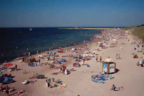 Tłum ludzi wypoczywa na plaży w Darłówku. Słońce, morze i piasek tworzą idealne warunki do relaksu.