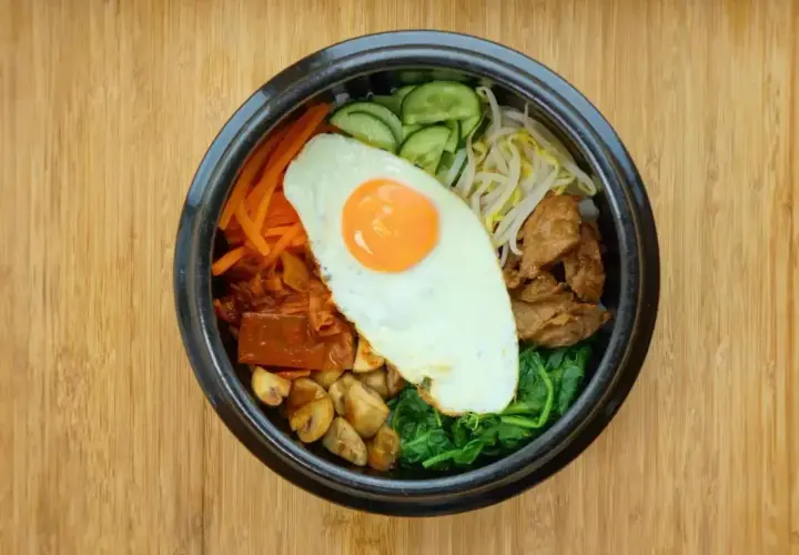 Kolorowe bibimbap, klasyczne danie kuchni koreańskiej, z jajkiem sadzonym, warzywami i mięsem.