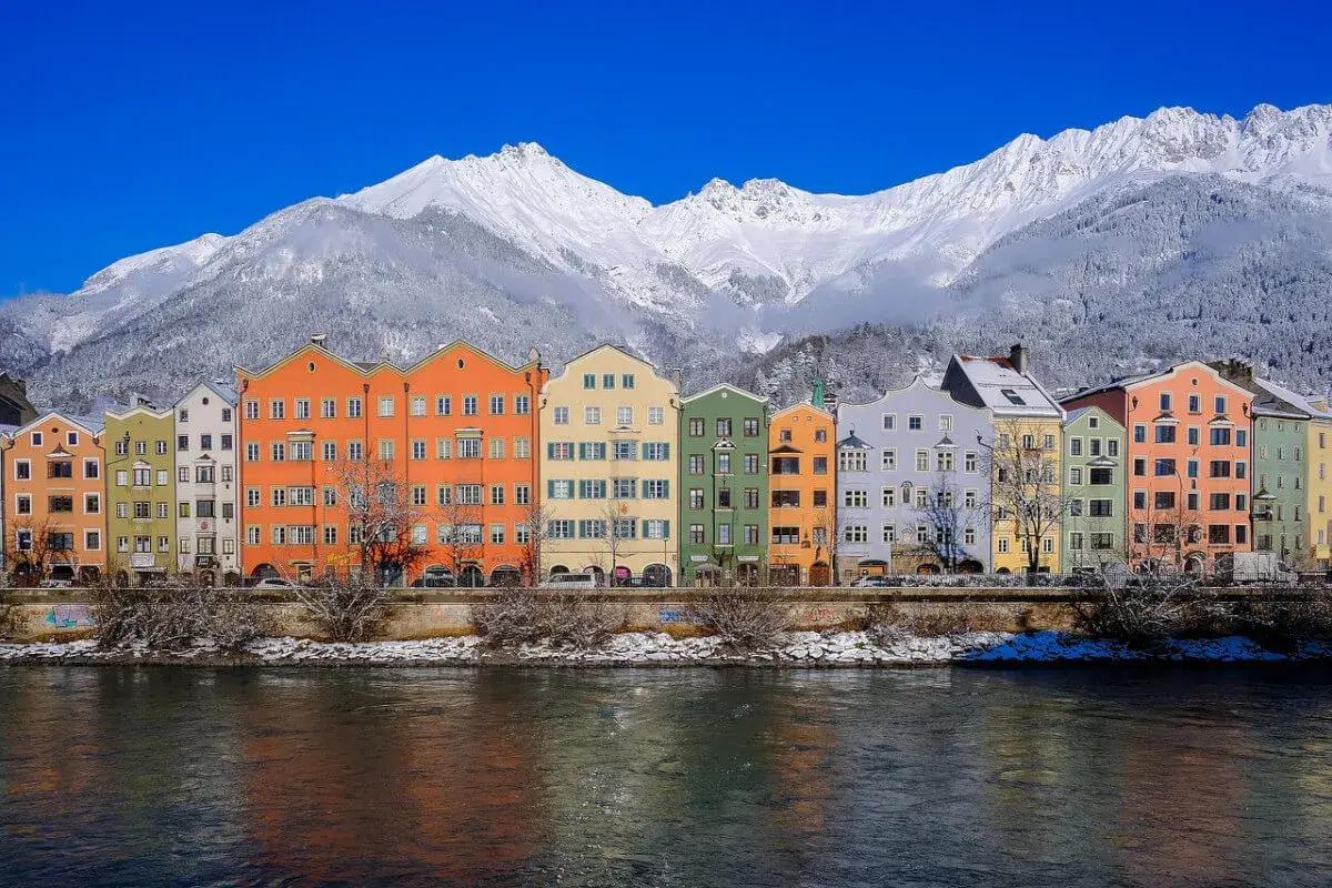 Kolorowe kamienice nad rzeką, w tle ośnieżone góry. To piękne Innsbruck atrakcje, które warto zobaczyć zimą.