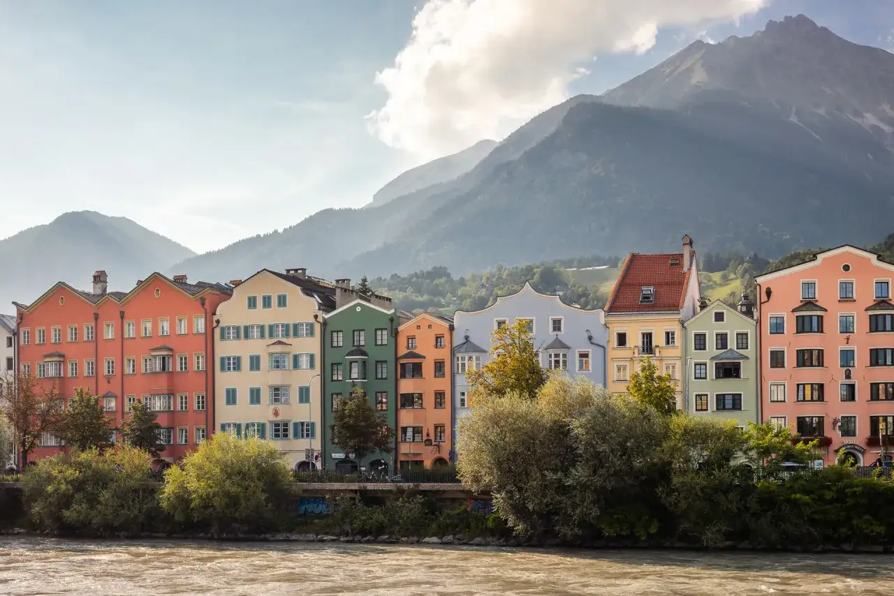 Kolorowe kamienice nad rzeką, w tle góry. To piękne Innsbruck atrakcje, które warto zobaczyć.