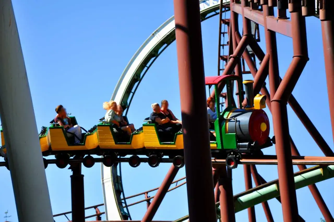 Pasażerowie bawią się na kolejce górskiej w kształcie lokomotywy w parku rozrywki Hansa Park.